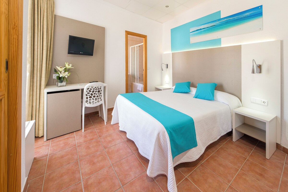 Une chambre d’hôtel comprenant un lit, un bureau, une chaise, une télévision et une salle de bain.