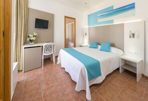 A hotel room with a bed, a desk, a chair, a TV, and a bathroom door. - Hostal Residencia Adelino (Sant Antoni de Portmany)
