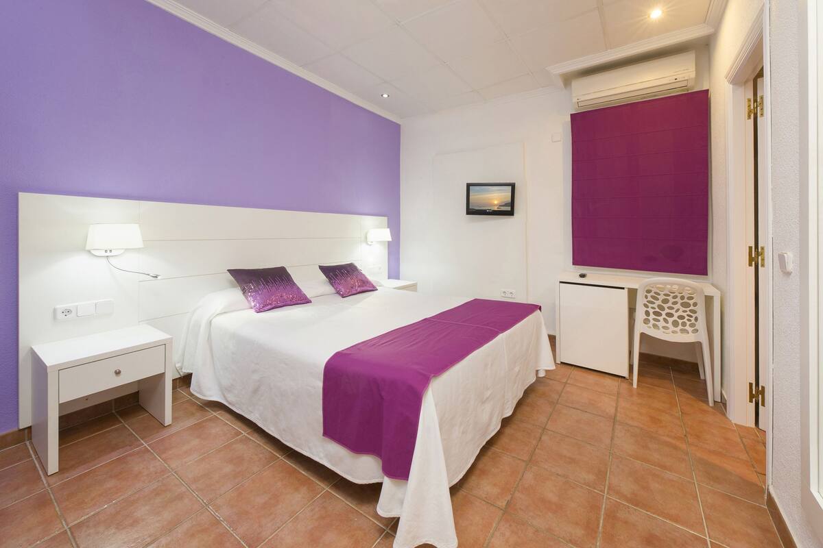 Ein Schlafzimmer mit einem Bett, Nachttischen, einem Schreibtisch und einem Sessel.