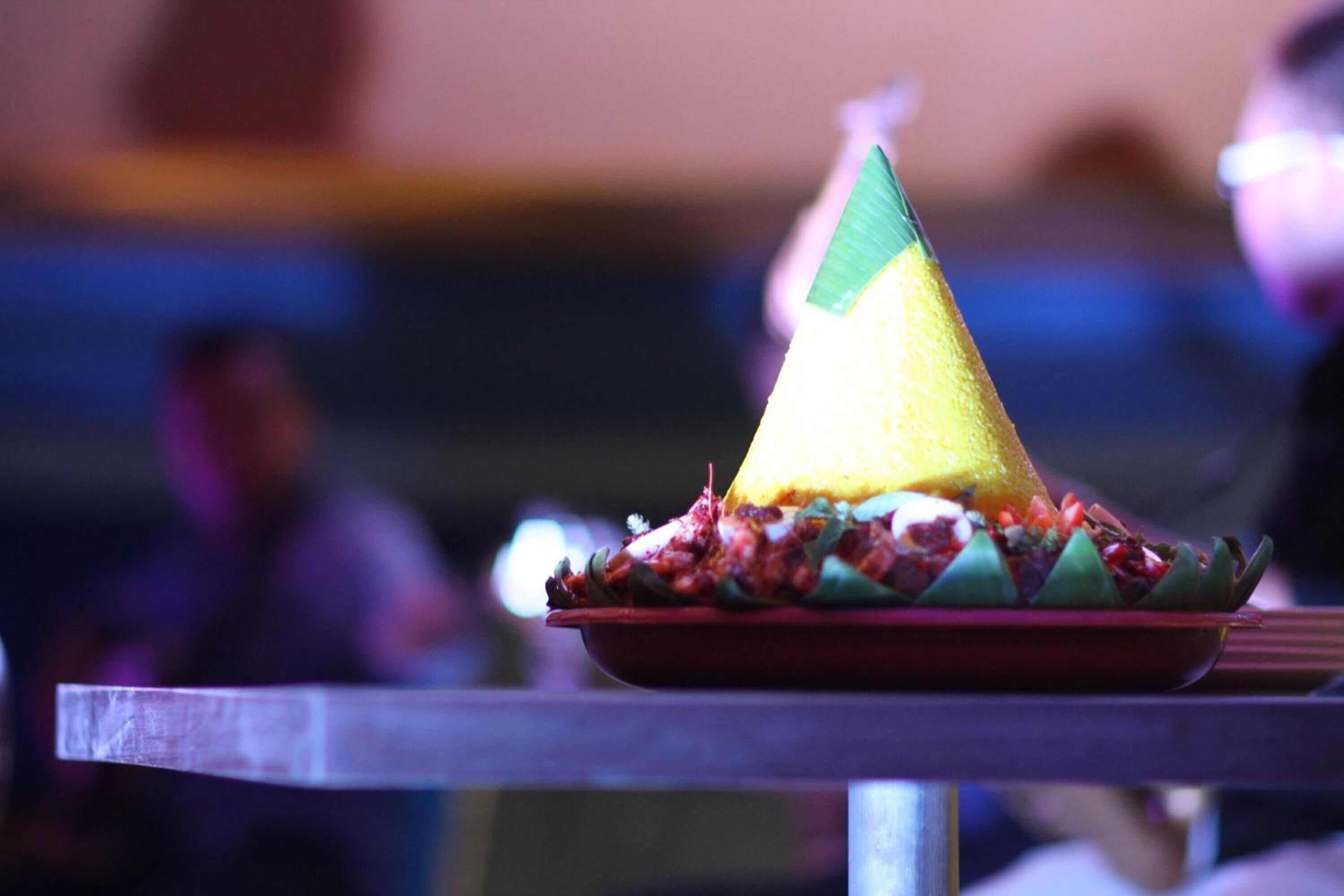A table with a plate of food, including a yellow cone-shaped item and a red plate.