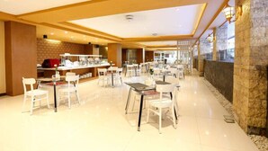 Un hall d’hôtel spacieux, doté de plusieurs espaces salon, d’un comptoir d’accueil et d’un mur décoratif en pierre.