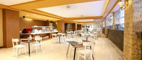 A spacious hotel lobby with multiple seating areas, a reception desk, and a stone accent wall.