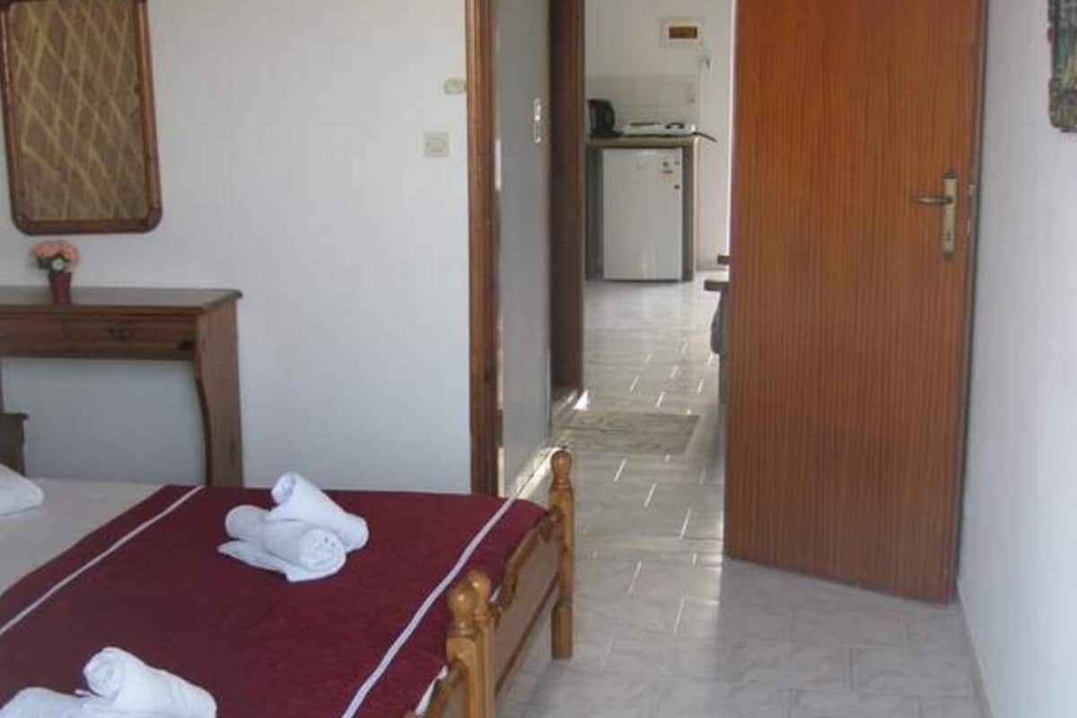 Una habitación de hotel con una cama de madera, una colcha roja y suelo de baldosas.
