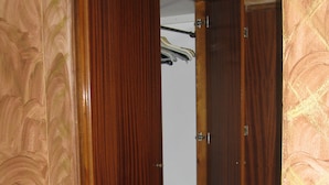 Un armari de fusta amb mirall, una barra penjant i un petit armari.