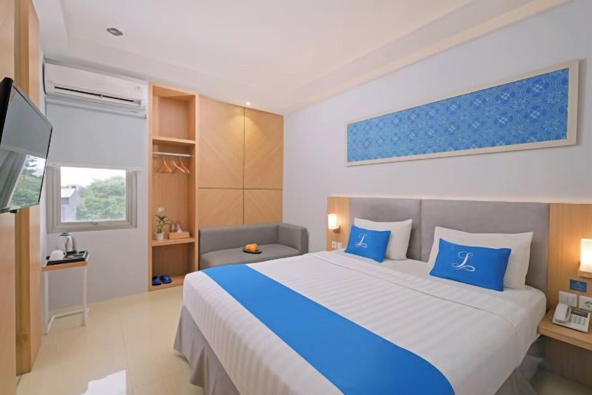 A hotel room with a bed, a television, a desk, and a wardrobe.