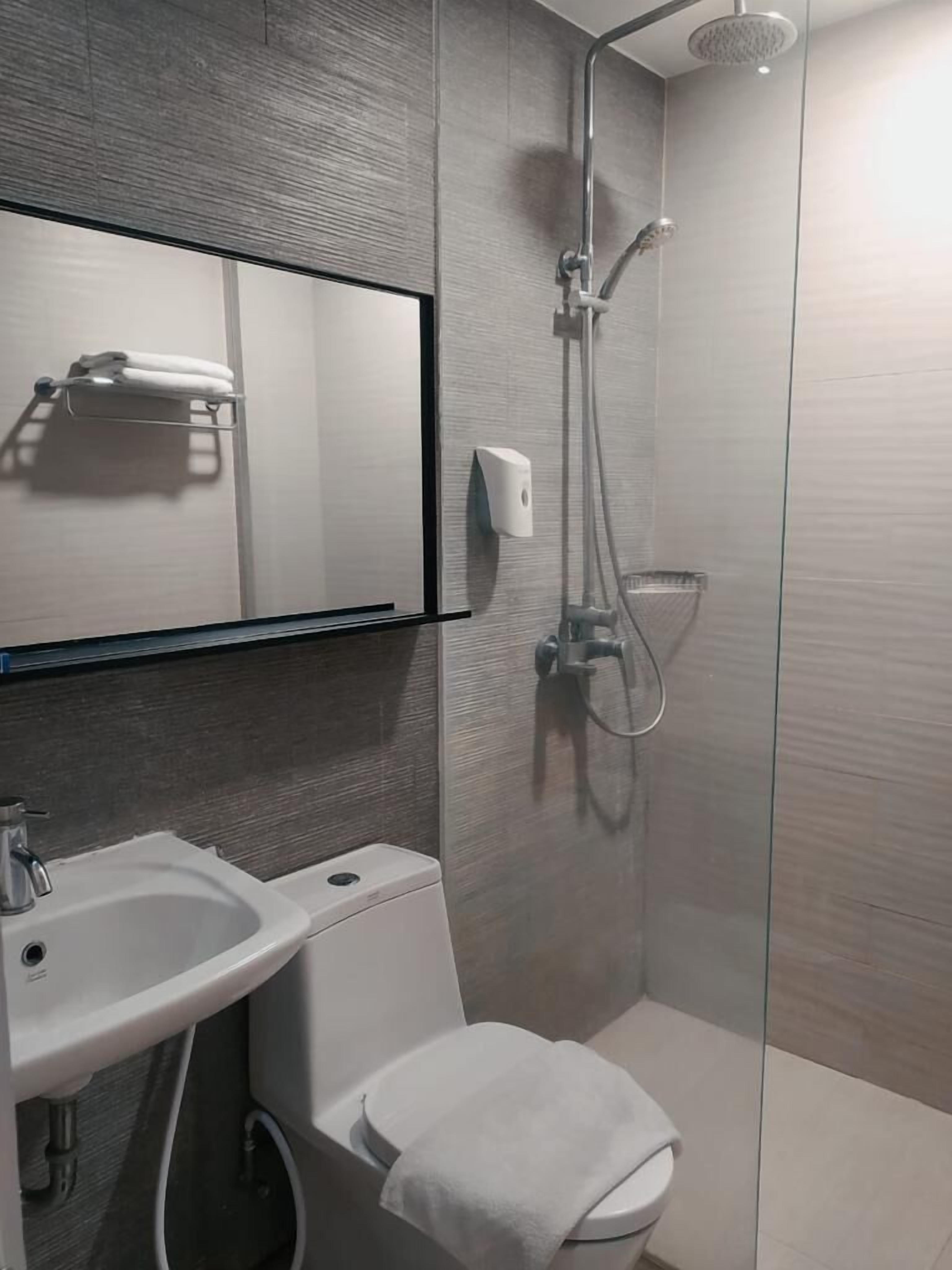 Un baño moderno con cabina de ducha de vidrio, un lavabo blanco y un inodoro.