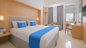 Une chambre d’hôtel avec un grand lit, une table de chevet, un bureau, une chaise et un téléviseur.
