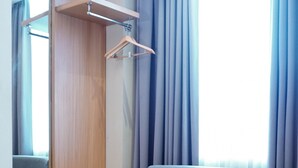Une pièce moderne avec un canapé gris, une table en bois dotée d’un porte-revues suspendu et une grande fenêtre ornée de rideaux bleus.