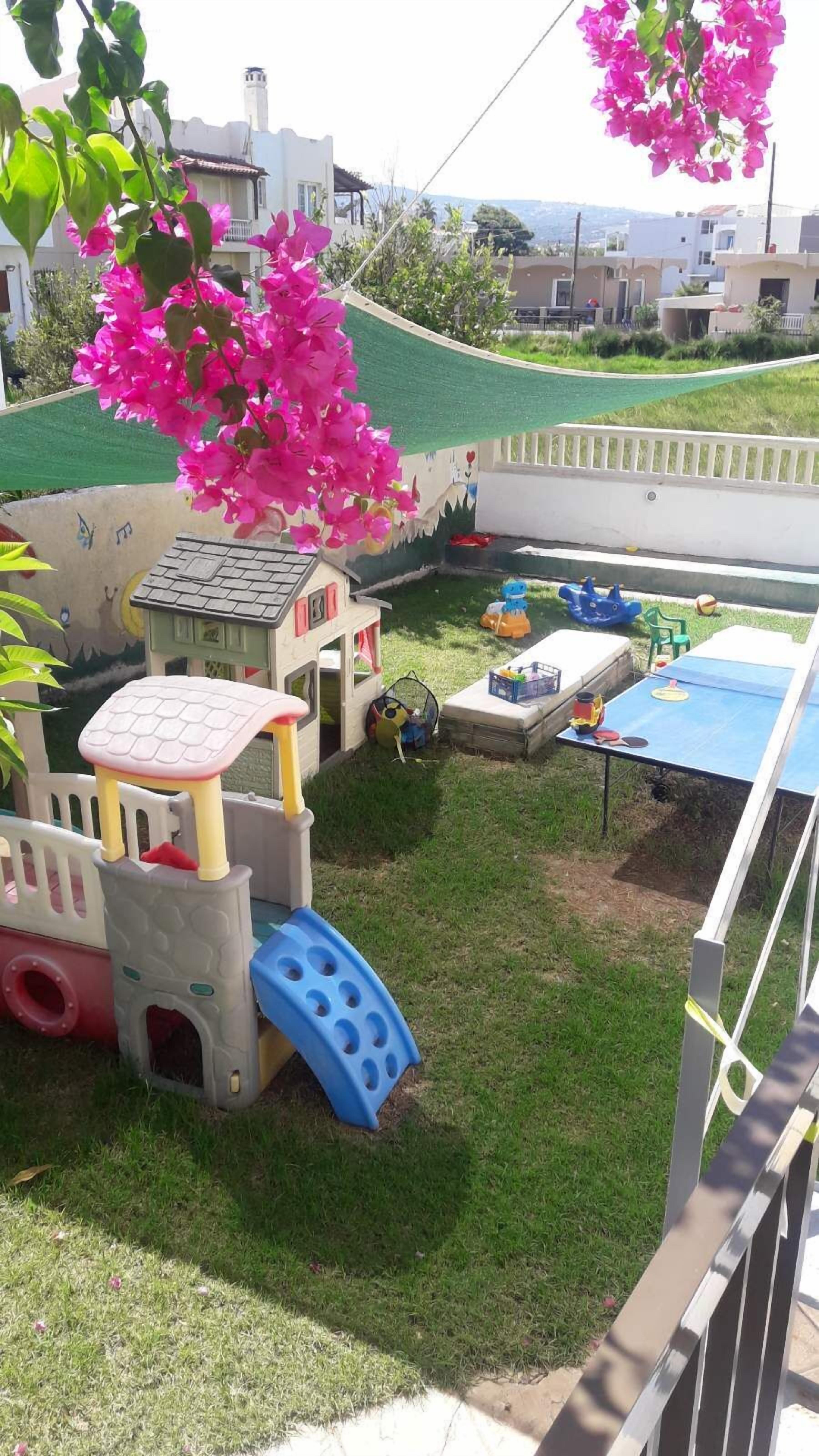 Un área de juegos infantiles con tobogán, estructuras para escalar y una casita.
