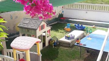 Un área de juegos infantiles con tobogán, estructuras para escalar y una casita.