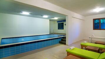 A spa area with a swimming pool, wooden loungers, and a small table with towels.