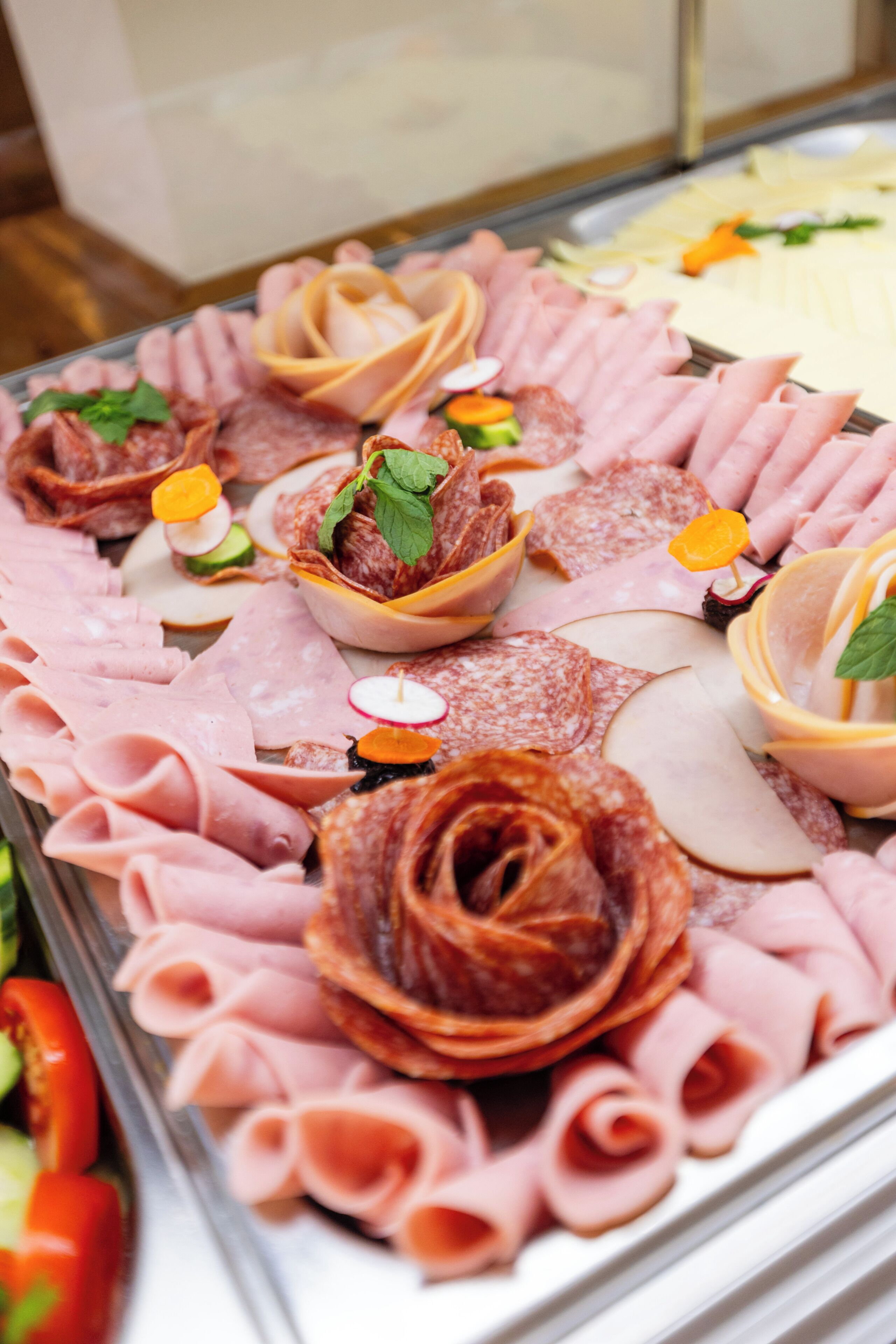 A charcuterie board with various meats, cheese, and garnishes.