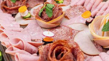A charcuterie board with various meats, cheese, and garnishes.