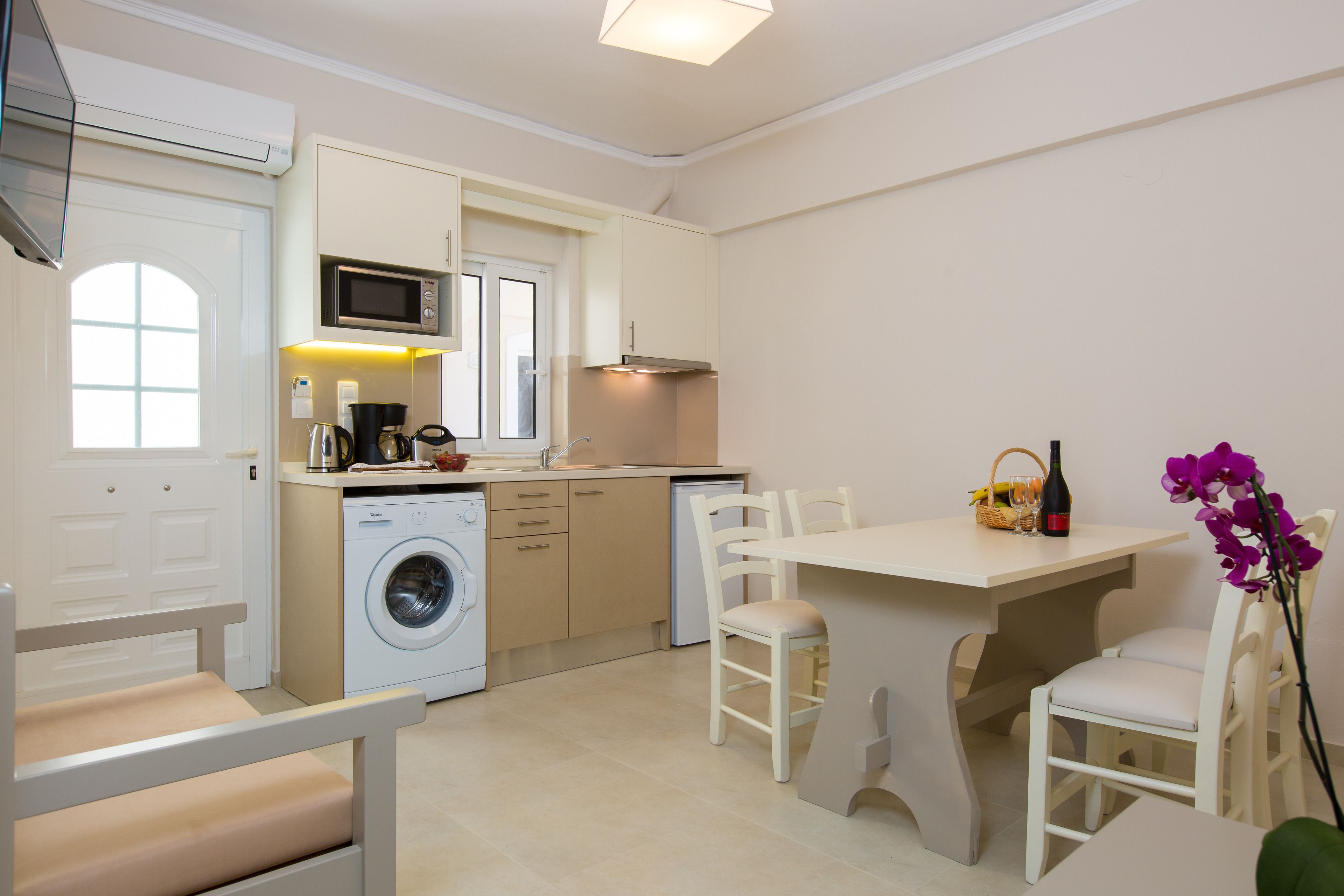 Une cuisine compacte équipée d’un lave-linge, d’un four à micro-ondes et d’un coin repas avec une table et des chaises.