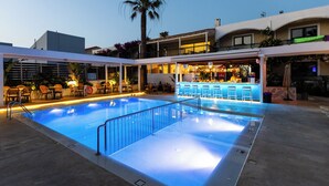 A swimming pool with a bar area, outdoor seating, and a palm tree. - Trefon Hotel Apartments and Suites (Rethymno)