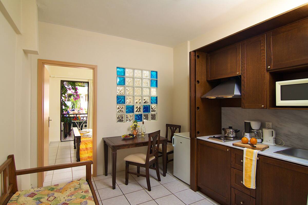 A compact kitchen with wooden cabinets, a microwave, and a small dining area with a table and chairs.