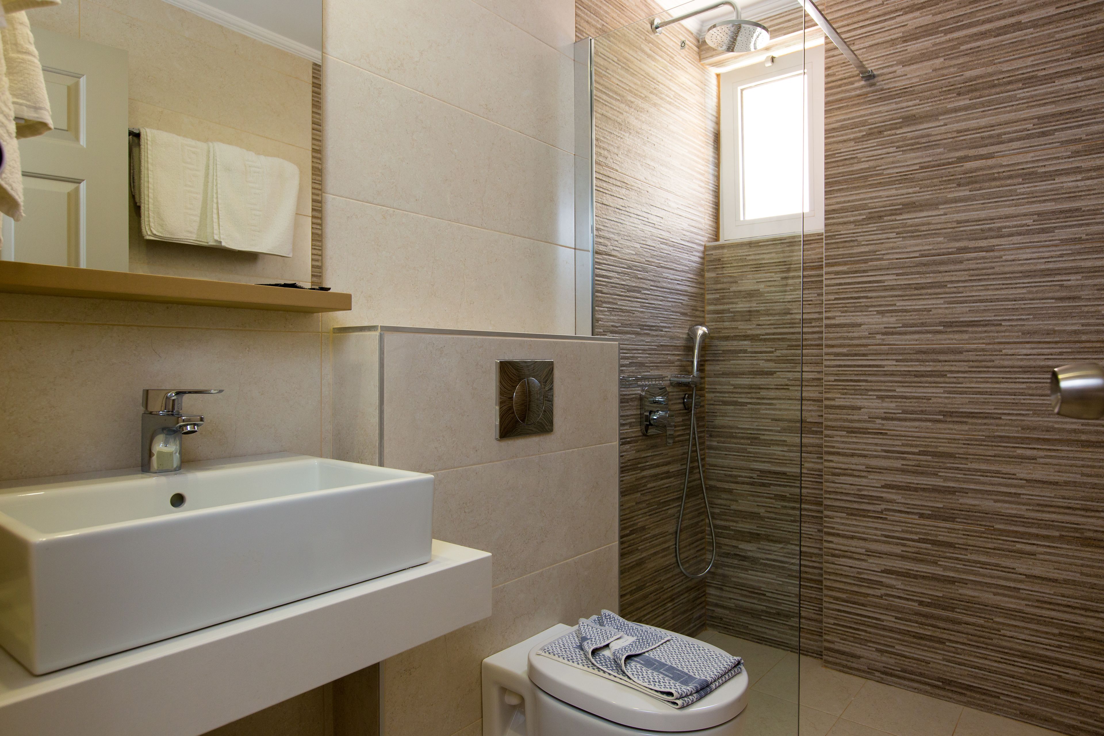 A modern bathroom with a white sink, a toilet, and a glass shower enclosure.