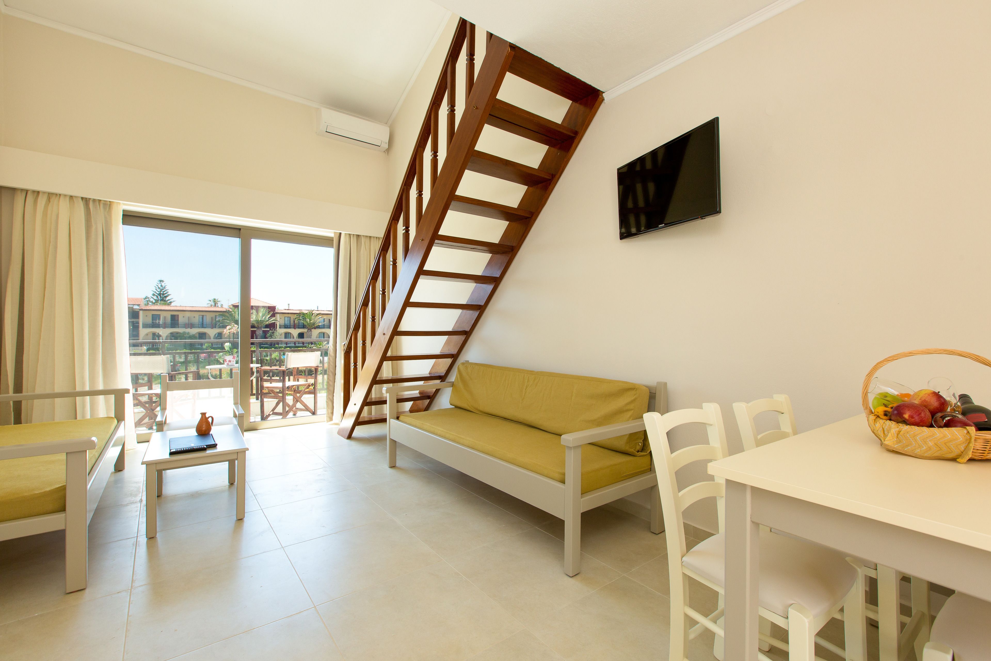 A modern living room with a sofa, a dining table, and a staircase.