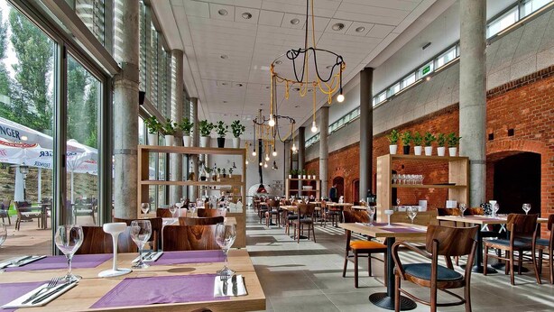 A spacious restaurant with high ceilings, exposed brick walls, and large windows. Tables are set with wine glasses and cutlery. - Hotel Forza (Poznan)