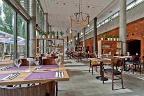 A spacious restaurant with high ceilings, exposed brick walls, and large windows. Tables are set with wine glasses and cutlery. - Hotel Forza (Poznan)