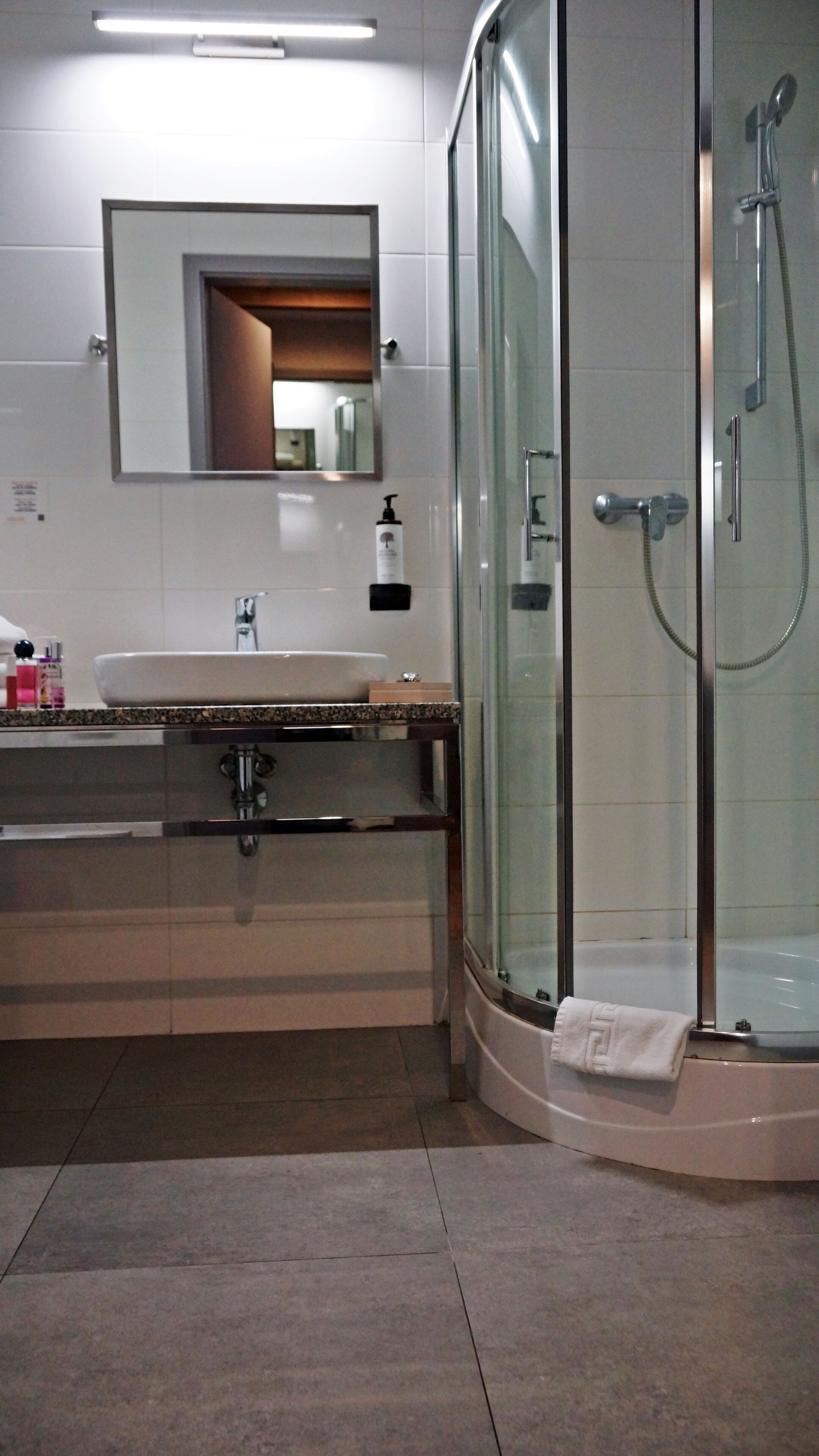 Un bany modern amb dutxa de vidre, un lavabo amb taulell de marbre i un mirall per sobre del lavabo.