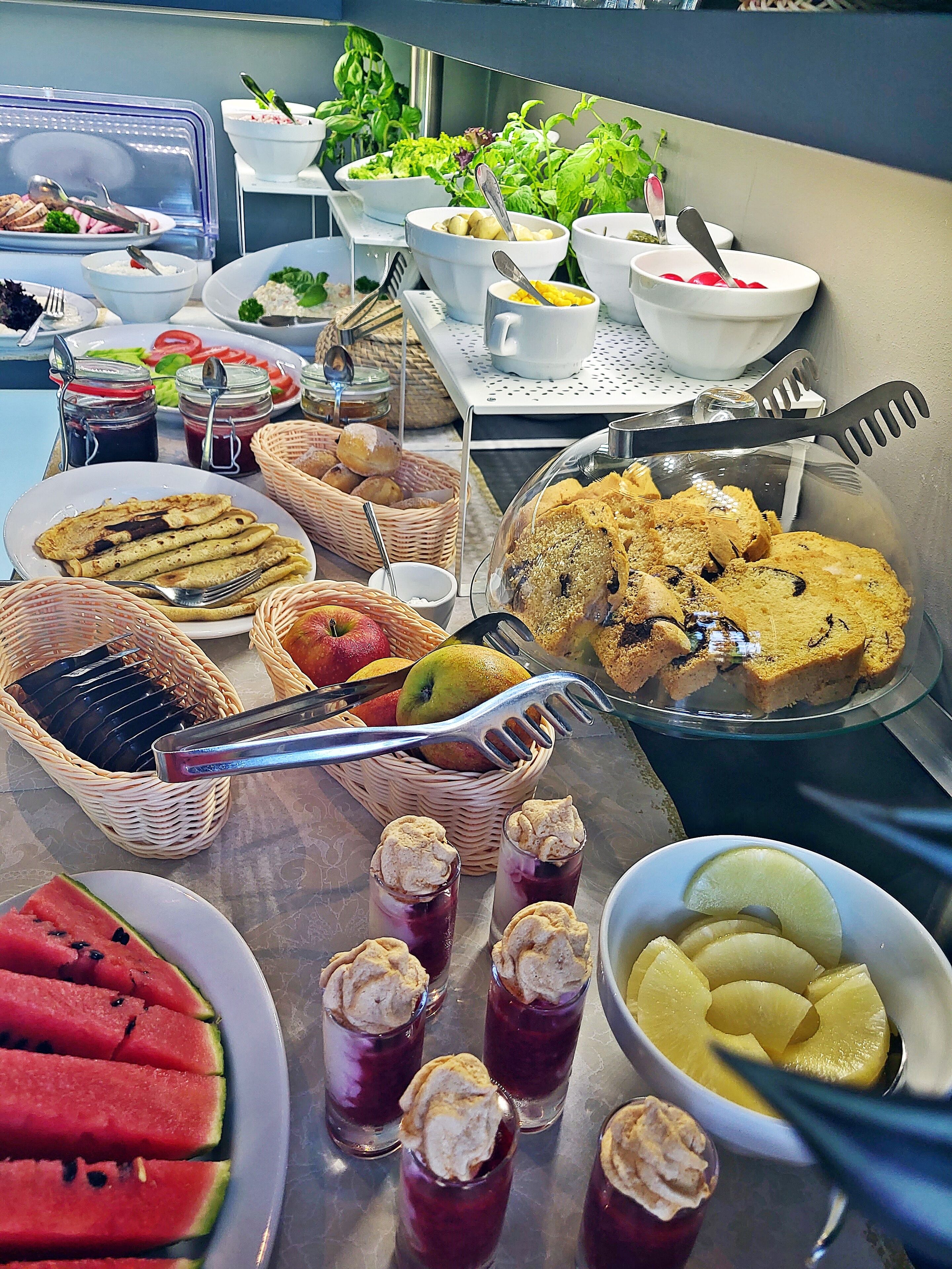A buffet table with various food items including fruits, desserts, and beverages.