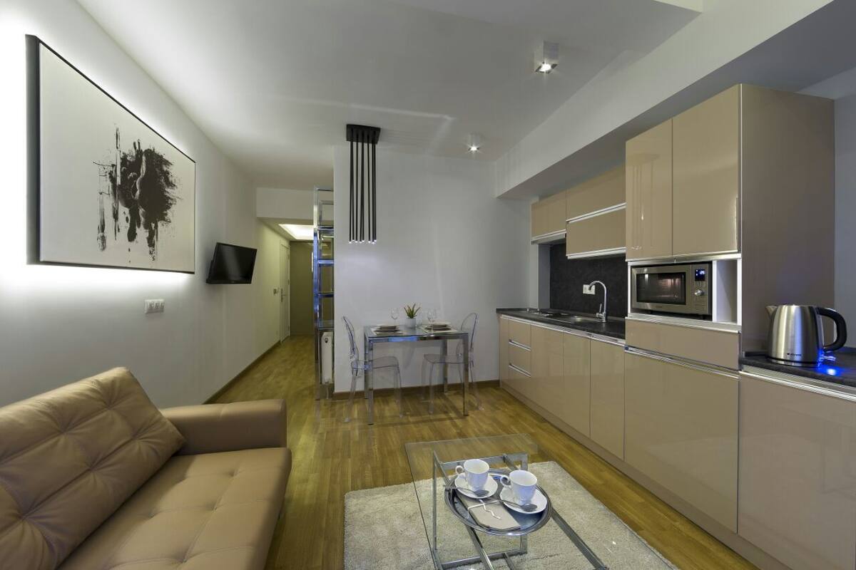 A modern kitchen with a dining area, a sofa, and a coffee table with cups and saucers.