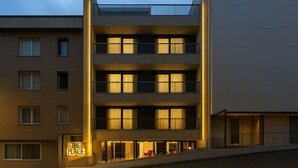 Et hotel med flere etager, med altaner, store vinduer og et skilt, der siger 'THE PLACE'.