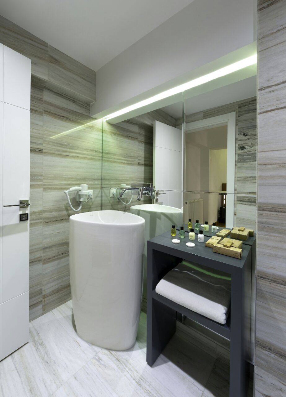A modern bathroom with a large white bathtub, a sink, and a vanity with toiletries.