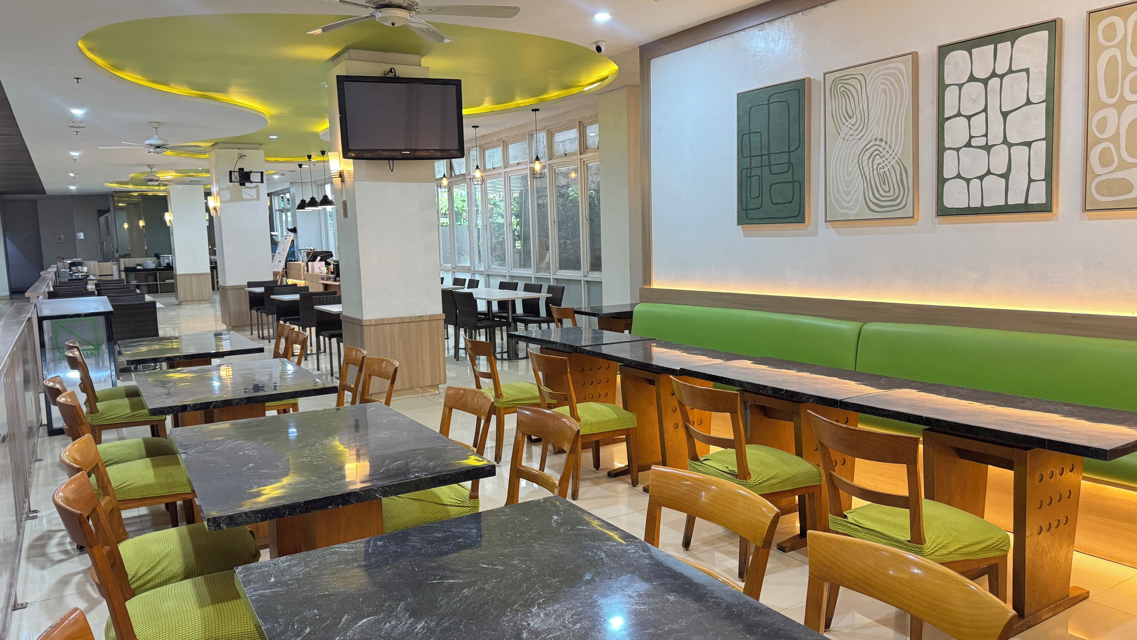 A restaurant interior with multiple dining tables, chairs, and a green booth area.