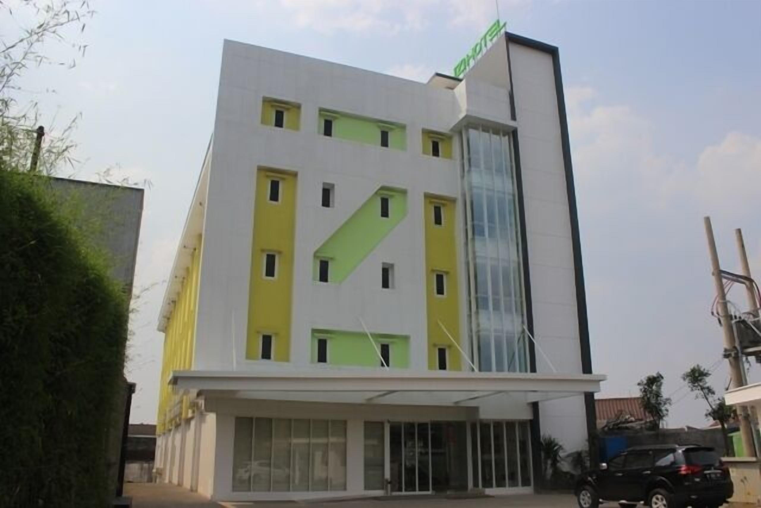 A modern hotel with a white and yellow facade, large windows, and a prominent vertical glass section.