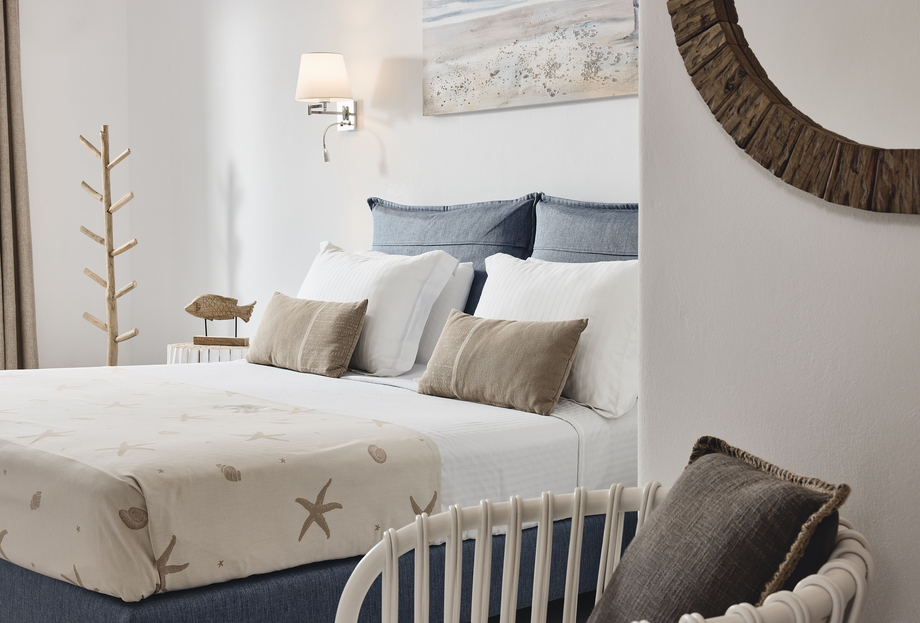 Un dormitorio ordenado con cama, almohadas, una mesita de noche y una lámpara.