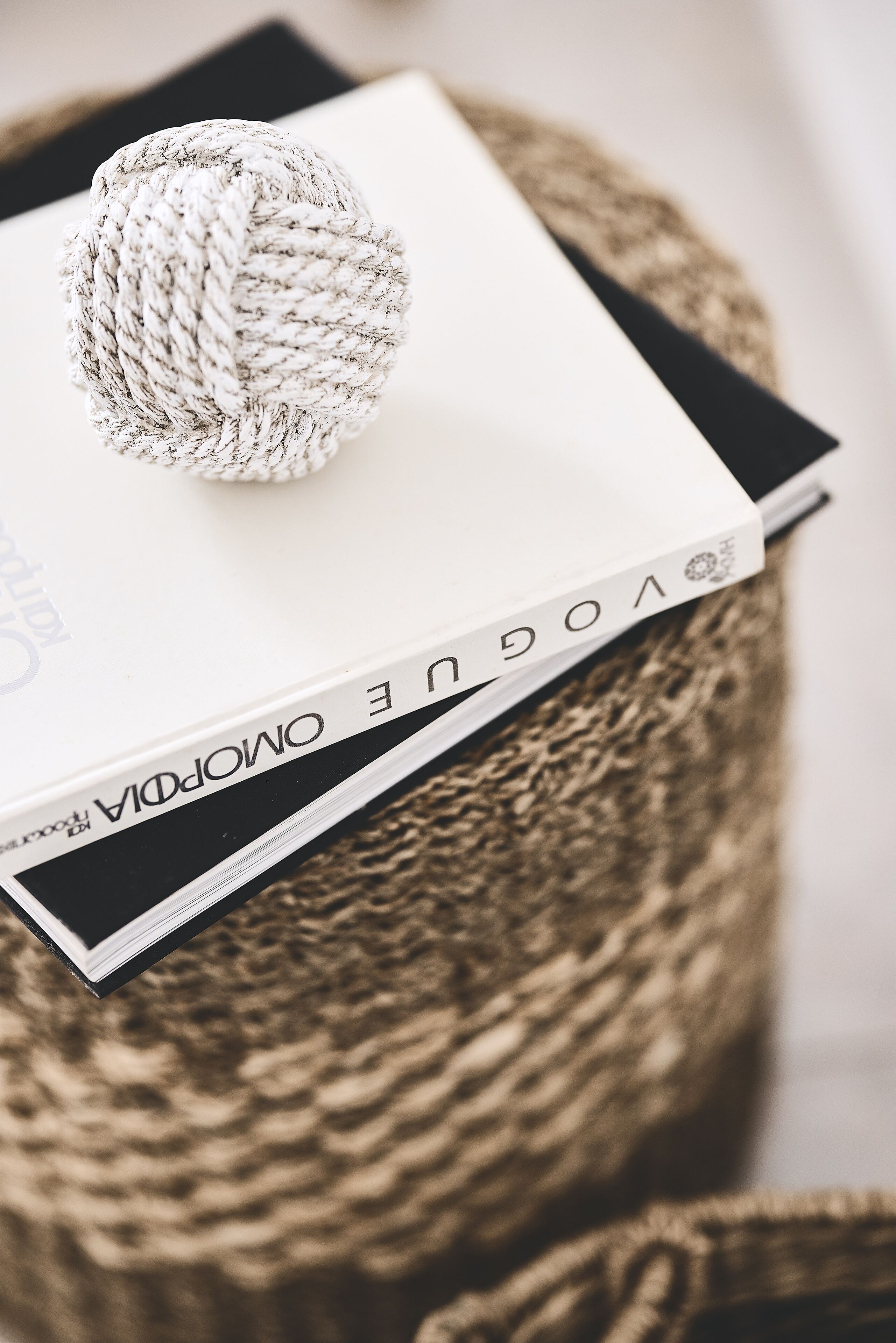 Un livre intitulé « Vogue Omopopa » posé sur un tabouret en osier.