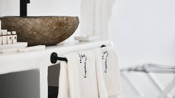 A bathroom with a stone sink, white towel racks, and neatly arranged toiletries.