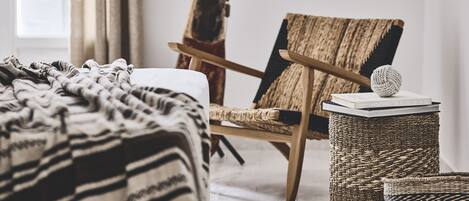 Un dormitorio acogedor con una cama, una silla y una mesita con un libro y una esfera decorativa.
