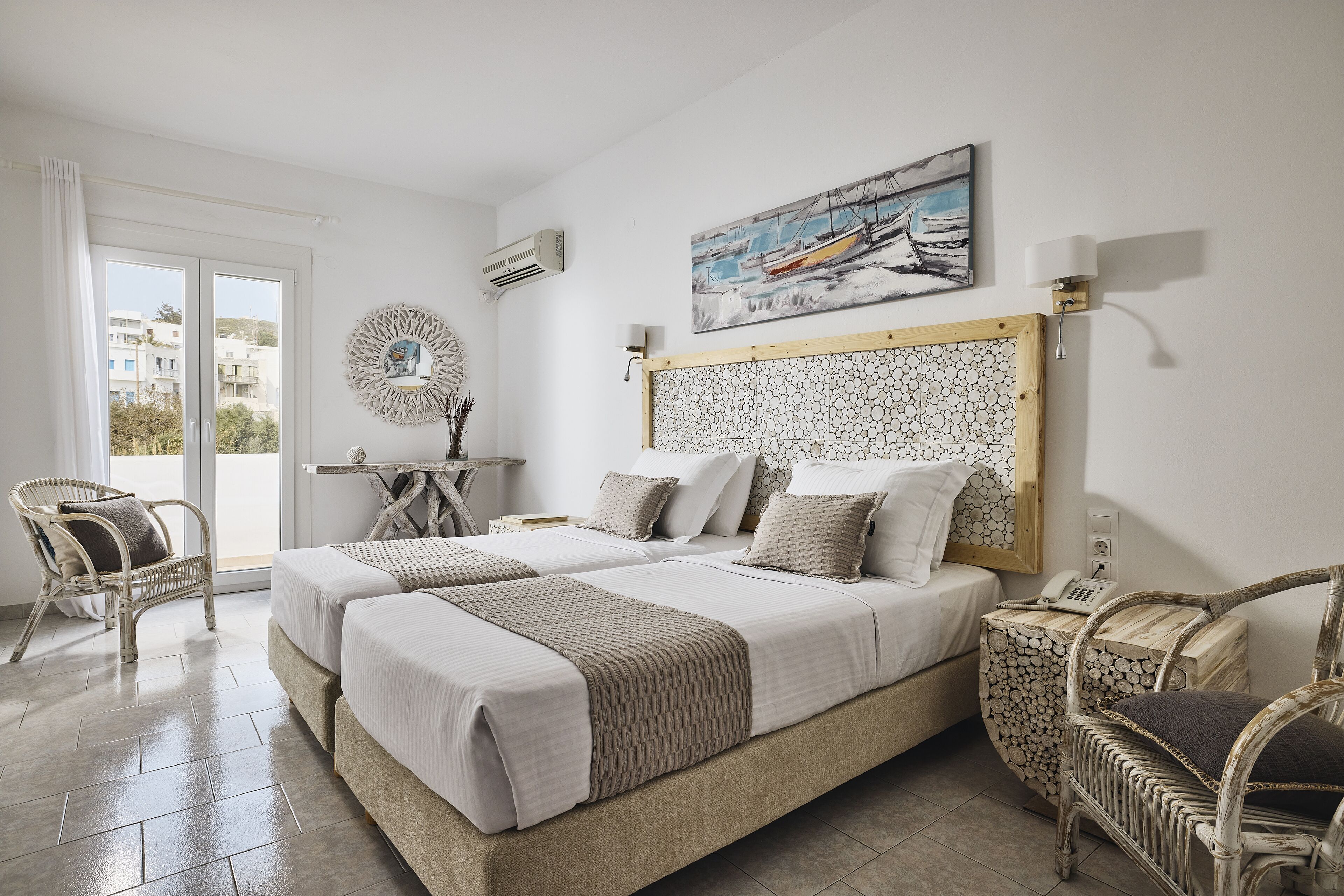 A hotel room with two beds, a large window, a painting, and a decorative wall piece.