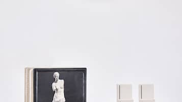 A framed artwork of a classical statue on a shelf, accompanied by a set of skincare products.