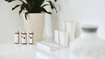A clean, minimalist setup with a potted plant, three small bottles, and a few white boxes on a reflective surface.