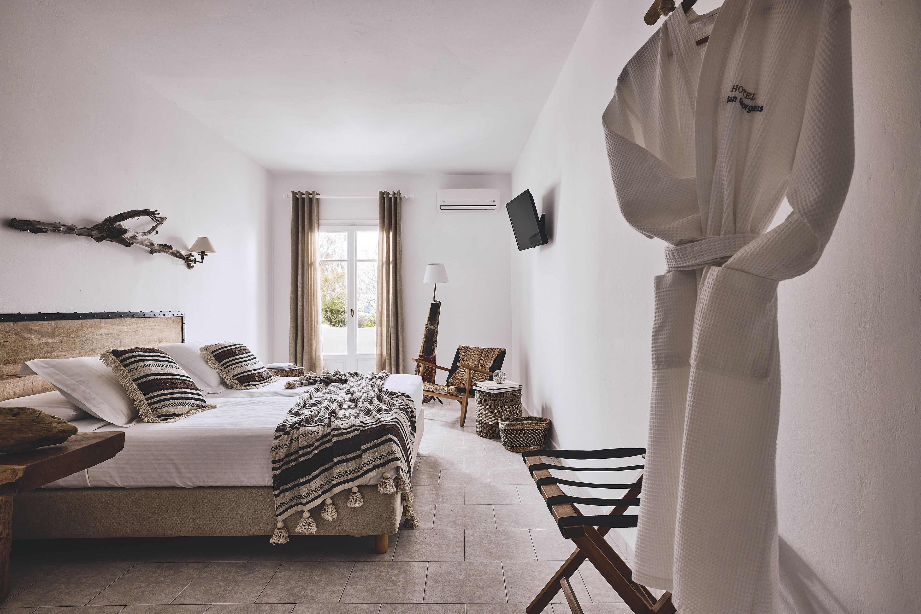 Un dormitorio con cama, mesita de noche, lámpara y bata colgada en la pared.