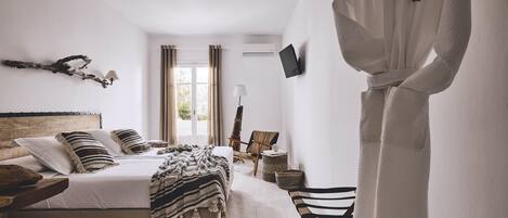 Un dormitorio con cama, mesita de noche, lámpara y bata colgada en la pared.