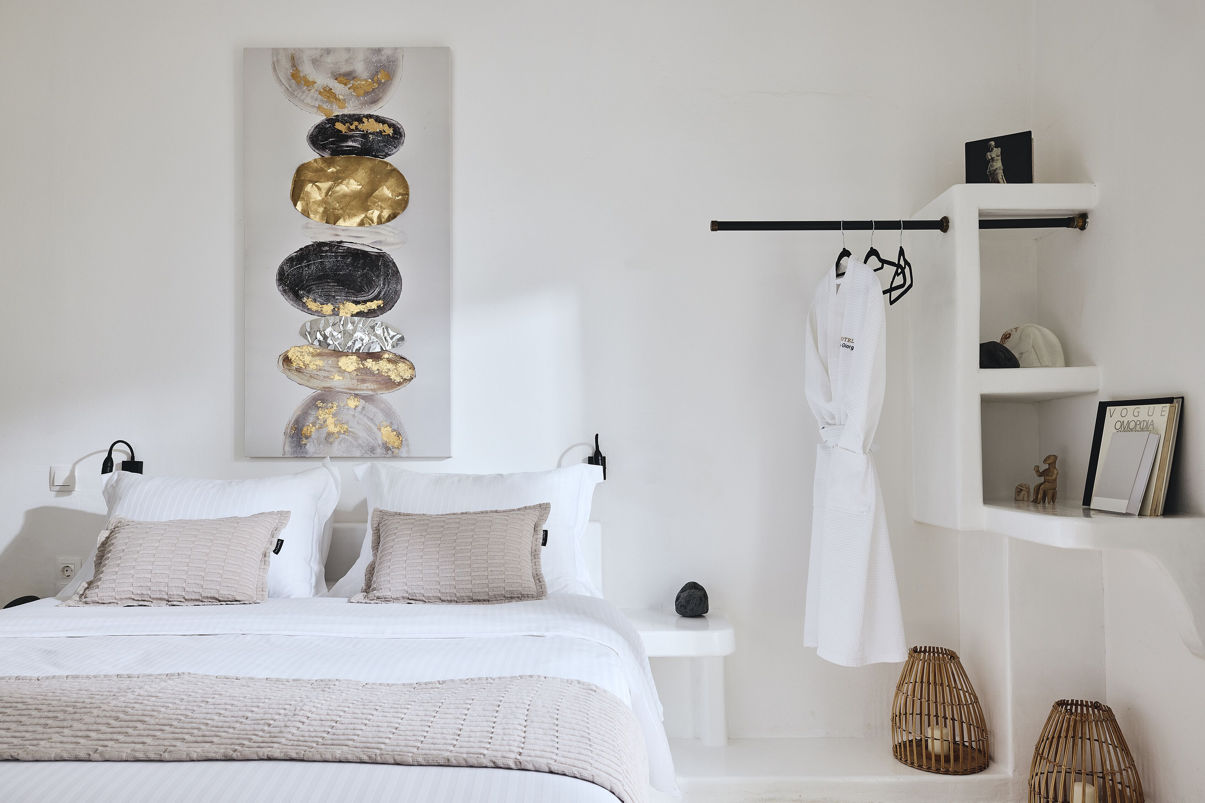 A modern bedroom with a bed, bedside tables, a robe hanging, and a wall art piece.