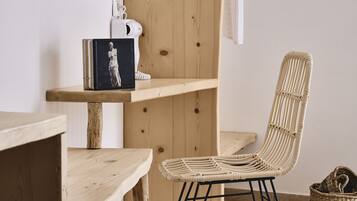 Una habitación con estantería de madera, una silla de mimbre y una cesta de mimbre.