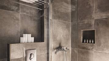 A modern shower area with a built-in shelf for toiletries, a towel rack, and a control panel.