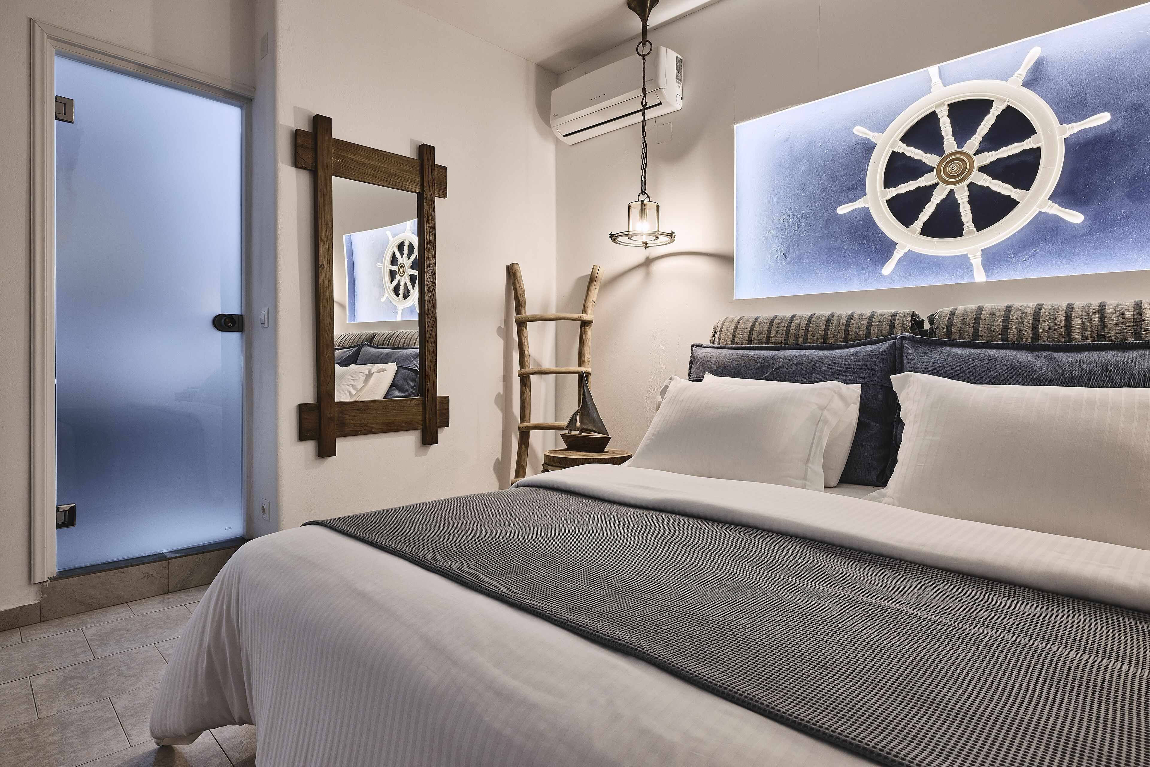 Una camera da letto con un letto, una scala in legno, un condizionatore d'aria a parete e un quadro con una grande ruota di timone.