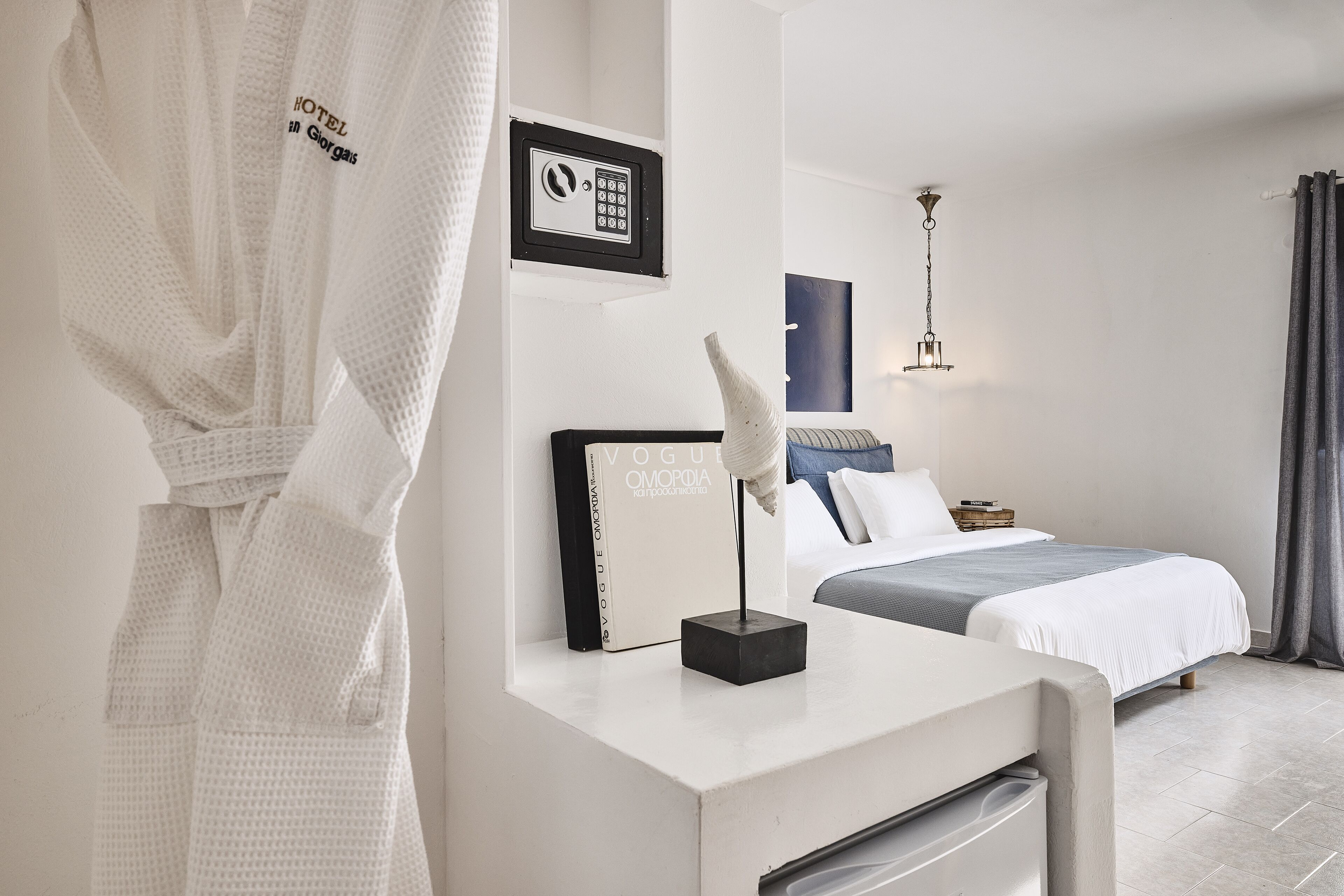 Une chambre d’hôtel avec un lit, un bureau doté d’une lampe, un peignoir accroché au mur et un tableau représentant un clavier de sécurité.