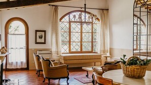 A cozy room with a large window, a chandelier, and a dining area with a table and chairs. - Ginestriccio (Bibbona)