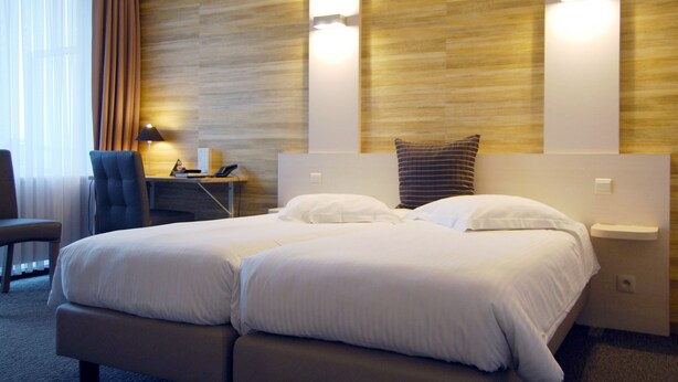 Habitación de hotel con una cama grande, un escritorio con lámpara y una silla.