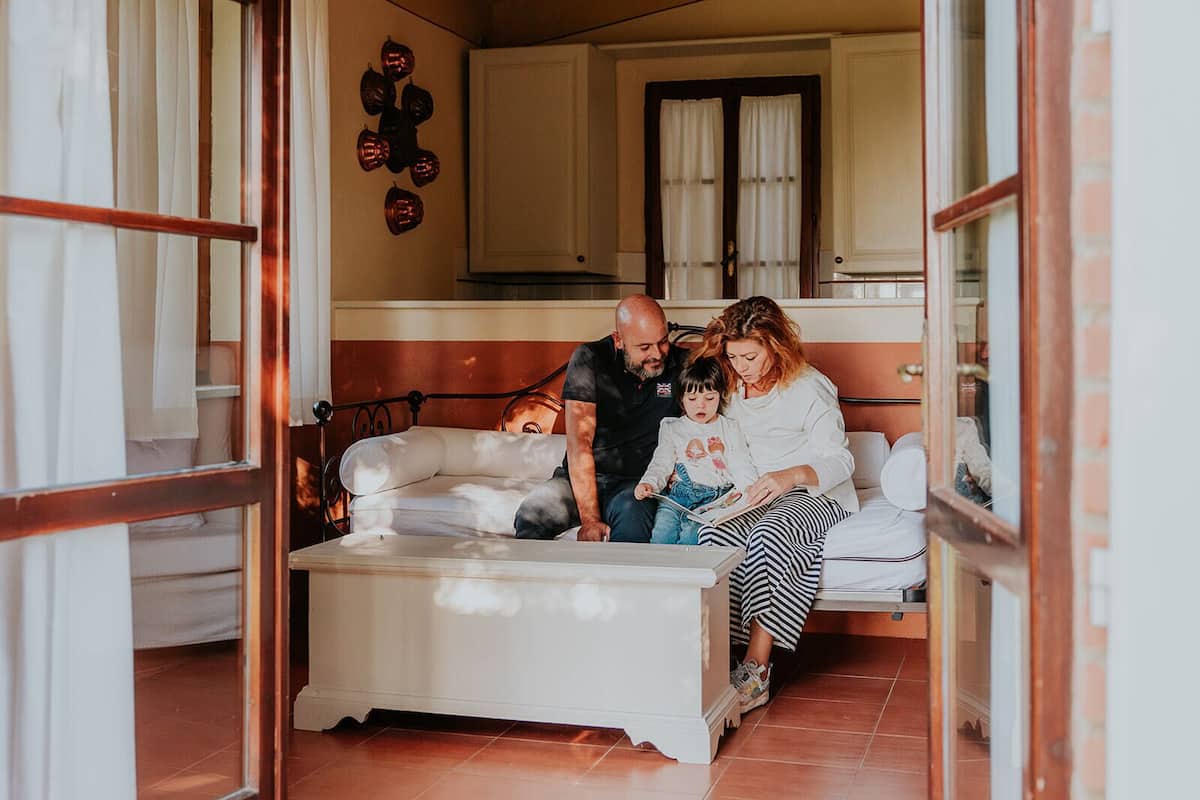 Une famille est assise sur un canapé dans une pièce où l’on aperçoit une cuisine au fond.