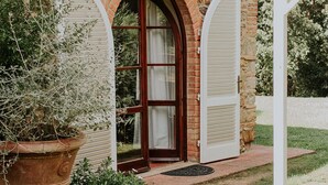 A stone building with a red-tiled roof, a wooden door, and white shutters. - Poggio Cornetto (Bibbona)
