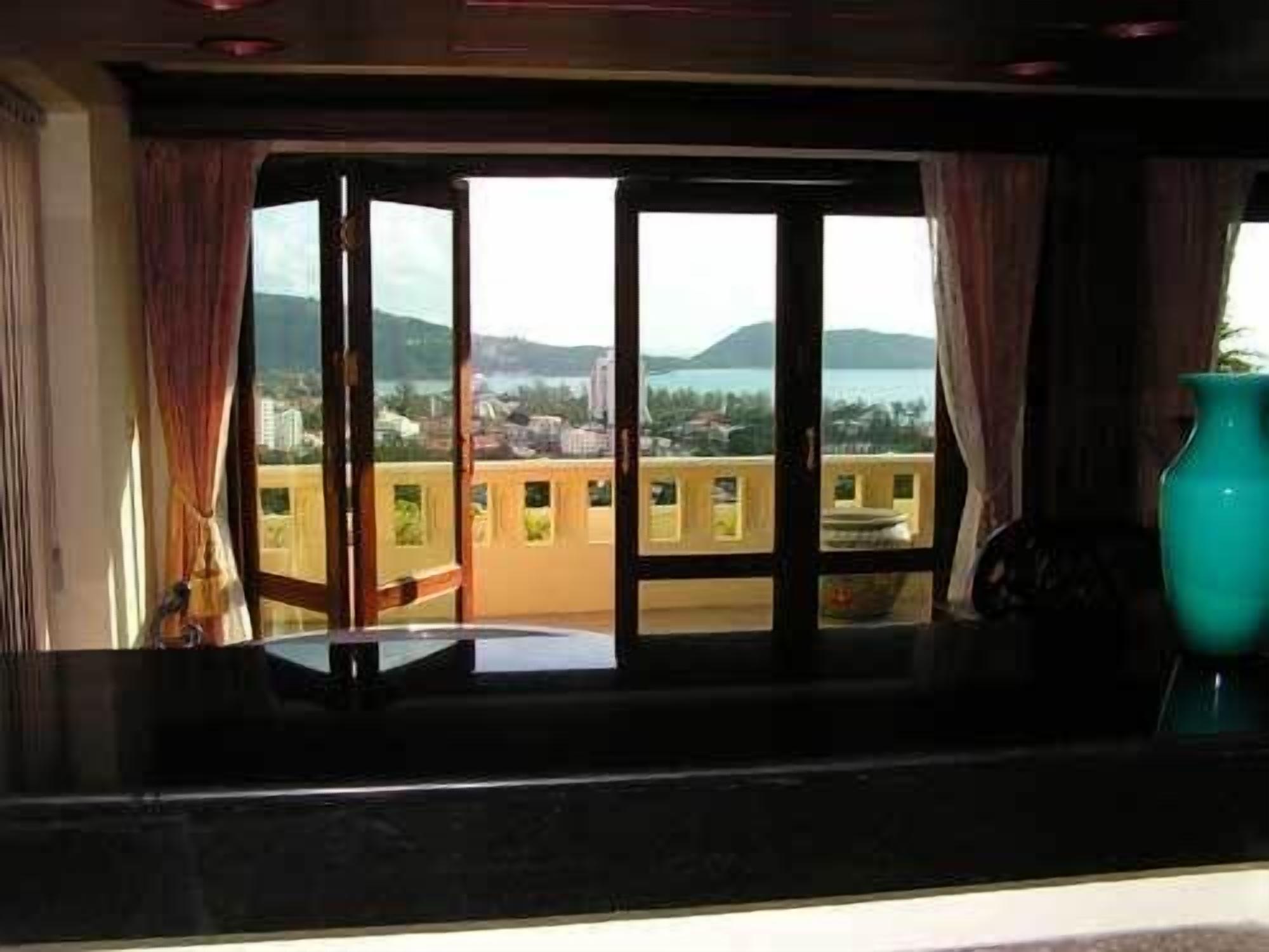Una habitación con un amplio ventanal que ofrece vistas a un paisaje urbano y montañas.